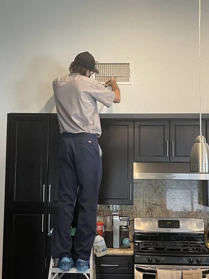 Technician inspecting an air vent during HVAC service in Natchitoches